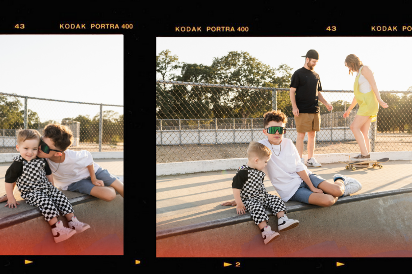 Rocklin lifestyle family portraits, big brother kissing toddler in checker overalls during skatepark session with parents in background.